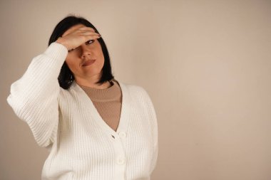 Kadın şakağına tek eliyle dokunuyor ve kötü bir baş ağrısının sinyalini veriyor. Duruşu rahatsızlığı vurguluyor. Sahne ağrı yönetimi ve rahatlama ihtiyacına odaklanıyor.