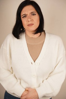 Kız ellerini karnının üstünde tutuyor, görünüşe göre rahatsız ya da acı içinde. Yüz ifadesi ve duruşu tedirginlik hissi veriyor. Bu jest fiziksel gerilimi vurgular.