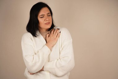 Kız ellerini karnının üstünde tutuyor, görünüşe göre rahatsız ya da acı içinde. Yüz ifadesi ve duruşu tedirginlik hissi veriyor. Bu jest fiziksel gerilimi vurgular.