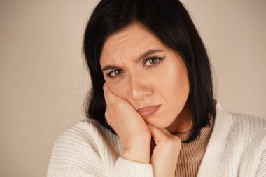 Genç bir kadın sakızını tek eliyle tutuyor, yüzünde rahatsızlık ifadesi var. Bu jest açıkça diş ağrısını ya da acıyı yansıtıyor. Sahne fiziksel bir huzursuzluğu ifade ediyor.