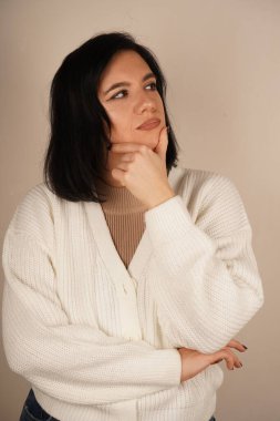 Genç bir kadın elini çenesinin altına koyar, derin düşüncelere dalmıştır. Bakışları, derin düşüncelere ve iç gözlemlere odaklanmış durumda. Sakin bir duruş, farkındalığı ve yansımayı sembolize eder.