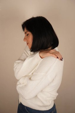 Bir kadın kolları göğsüne çarpıştı, özgüveni ve azmi simgeliyor. Duruşu değişmez bir bağlılığı var. Kadın kendine güvenerek duruyor ve gülümsüyor.