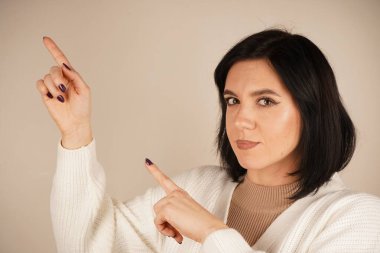 Genç kadın iki işaret parmağıyla tek bir yönü işaret ediyor. Bu da yolu gösteriyor. Duruşu özgüvenli ve anlamlı. Amaç ve berraklıkla dolu bir jest.