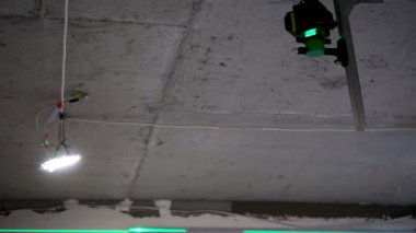 A green laser level beam shines brightly on the ceiling, helping to accurately level a ceiling model