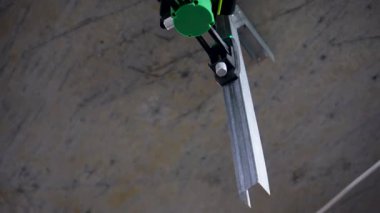 A sleek green laser level, turned off, stands on the bare floor of a partially constructed room