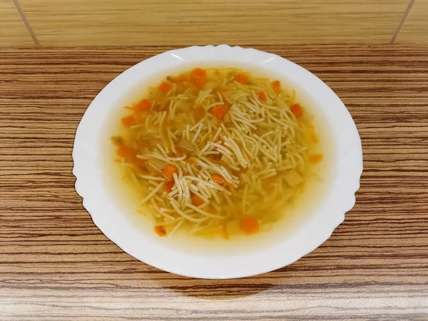 面条汤 配上胡萝卜和欧芹 在一个白色陶瓷盘中 — 图库照片