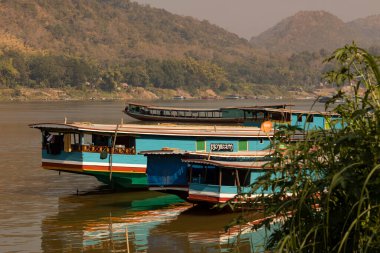 Luang Prabang, Laos - 15 Aralık 2019, Luang Prabang, Laos 'tan geçerken Mekong Nehri kıyısına demirlemiş insanları ve malları taşımak için büyük mavnalar.