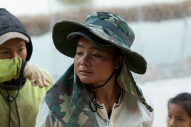 Luang Prabang, Laos - 15 Aralık 2019: Kadın, Luang Prabang, Laos 'tan geçerken Nam Khan nehrinin kıyısına taşlı bir Gabion duvarı inşa etmek için çalışıyor