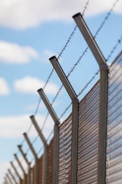 Metal fence with rusty and dangerous barbed wire, an obstacle commonly used to preserve private property