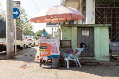 Yangon, Myanmar - 19 Aralık 2019: Bir kadın tezgahında betel fındık, areka ve tütün, Yangon, Burma, Myanmar satan bir sandalyede uyuyor