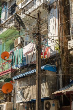 Yangon, Myanmar - 19 Aralık 2019 Yangon, Burma, Myanmar 'da tehlikeli elektrik kablolarıyla çevrili bir elektrik direği.