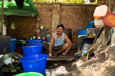 Yangon, Myanmar - 19 Aralık 2019: Gülümseyen bir Birmanyalı, Yangon, Burma, Myanmar 'daki sokak yemekhanesinde giysilerini yıkıyor.
