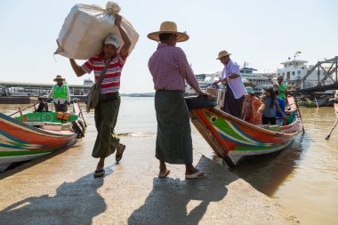 Yangon, Myanmar - 19 Aralık 2019: Yangon, Burma, Myanmar 'da Botahtaung Pagoda yakınlarında Yangon Nehri kıyısında bir adam büyük bir bohçayla bottan indi.