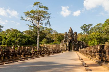 Access road to Bayon Temple in the ancient city of Angkor, Cambodia, guarded by dozens of statues of warriors carved in stone clipart