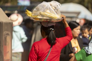 Bagan, Myanmar - 25 Aralık 2019 Bagan, Myanmar 'da bir kadın kafasında yemek tepsisiyle sokakta yürüyor.