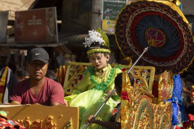 Bagan, Myanmar - 25 Aralık 2019: Geleneksel kıyafetler giymiş küçük bir kız, Theravada Budizmi geleneğine göre Shinbyu sırasında ata biniyor.