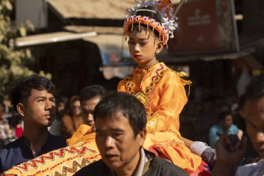 Bagan, Myanmar - 25 Aralık 2019: Geleneksel kıyafetler giymiş küçük bir kız, Theravada Budizmi geleneğine göre Shinbyu sırasında ata biniyor.