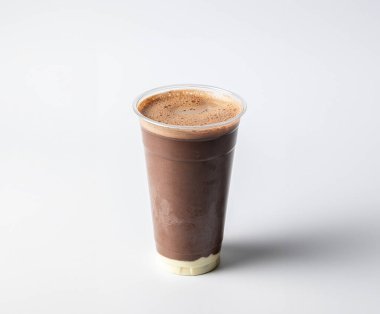 Arkaplanda vanilyalı ya da beyaz çikolatalı büyük bir bardak çikolatalı milkshake.