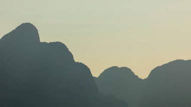 Dev karst dağlarının siluetleri yağmur ormanlarıyla kaplı, gün batımında, Vang Vieng yakınlarında, Laos 'ta.