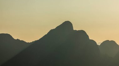 Dev karst dağlarının siluetleri yağmur ormanlarıyla kaplı, gün batımında, Vang Vieng yakınlarında, Laos 'ta.