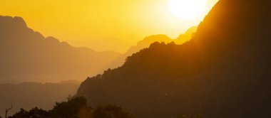 Gökyüzü ve manzara yoğun turuncularla donatılmıştır. Havada yüzen parçacıklar adeta bir rüya gibidir. Vang Vieng, Laos, Güneydoğu Asya yakınlarında.