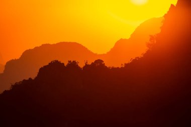 Farklı dağların siluetleri giderek soluklaşıyor ve uzaklaşıyorlar. Gün batımında inanılmaz bir manzarada, Vang Vieng, Laos yakınlarında.