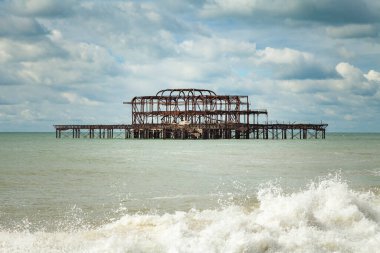 Brighton, İngiltere - 18 Eylül 2013: İngiltere 'nin güneyindeki Brigthon kasabasında sahilden bulutlu bir günde Batı İskelesi' nin terk edilmiş ve paslanmış yapısının görüntüsü.