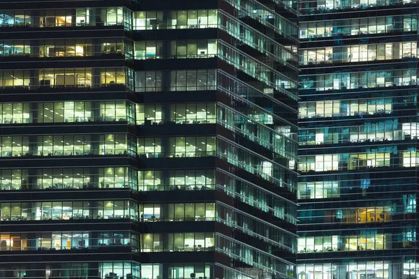 Geceleri aydınlatılmış çelik ve cam gökdelen binalar, evler ve ofisler.