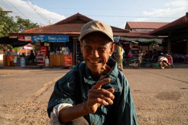 Pakse, Laos - 5 Aralık 2019: Yaşı ilerlemiş yaşlı bir adam, bana Pakse 'deki Bai Don pazarında gülümseyen bir bileyici olarak çalışmalarını açıklıyor.