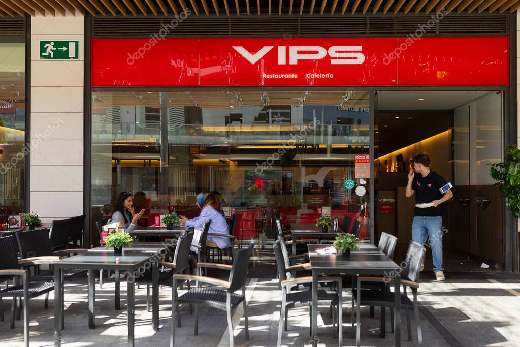 Zaragoza, Spain - 30 april, 2025: Some women sitting at an outdoor table of a VIPS restaurant in Puerto Venecia, the waiter comes out to serve them