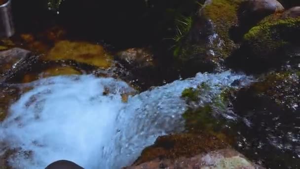 一个漂亮的女孩在高山瀑布边喝水 一边在山上爬山解渴 高质量的4K镜头 — 图库视频影像