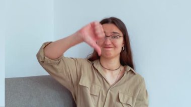 Genç ve çekici bir kız hayal kırıklığıyla baş parmağını kaldırıyor. Yüksek kalite 4k görüntü