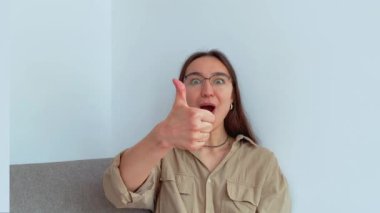 Genç ve çekici bir kız şaşırdı ve baş parmağını kaldırdı. Yüksek kalite 4K görüntü.