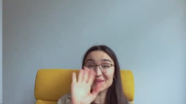 Genç ve çekici bir kız arkadaşlarını selamlamak için elini sallıyor. Yüksek kalite FullHD görüntüler.