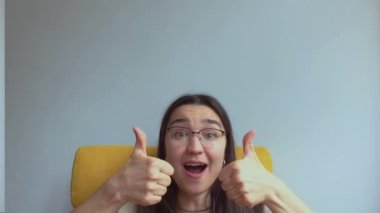 Genç ve çekici bir kız şaşırdı ve baş parmağını kaldırdı. Yüksek kalite 4K görüntü.