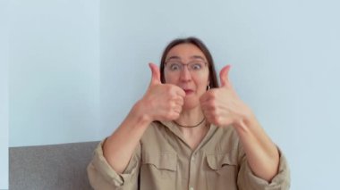 Genç ve çekici bir kız şaşırdı ve baş parmağını kaldırdı. Yüksek kalite 4K görüntü.