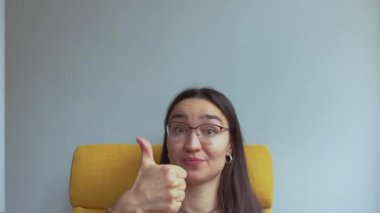 Genç ve çekici bir kız şaşırdı ve baş parmağını kaldırdı. Yüksek kalite 4K görüntü.