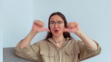 Genç ve çekici bir kız kafasını negatif bir şekilde sallar ve baş parmağını aşağı gösterir. Yüksek kalite 4k görüntü