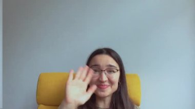 Genç ve çekici bir kız arkadaşlarını selamlamak için elini sallıyor. Yüksek kalite FullHD görüntüler.