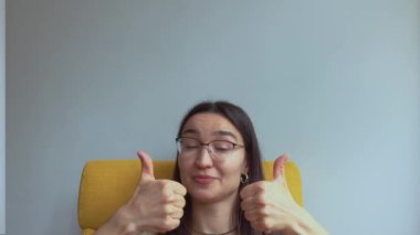 Genç ve çekici bir kız şaşırdı ve baş parmağını kaldırdı. Yüksek kalite 4K görüntü.