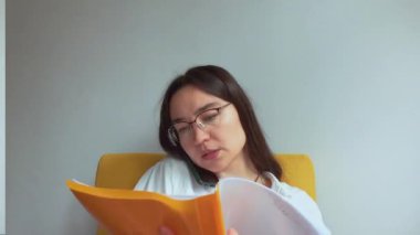 Genç ve çekici bir iş kadını telefonda konuşur ve belgelere bakar. Yüksek kaliteli FullHD görüntüler