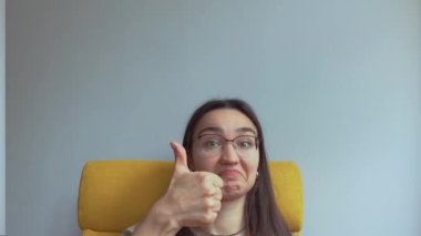 Genç ve çekici bir kız şaşırdı ve baş parmağını kaldırdı. Yüksek kalite 4K görüntü.