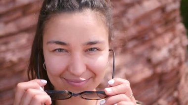 Leopar gömlekli manken muhteşem bir kayanın arka planında poz veriyor. Güneş gözlüklü çekici kız modeli kameraya bakıyor ve gülümsüyor..