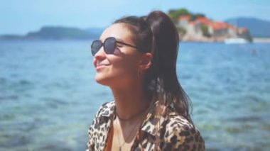 Muhteşem bir deniz manzarasına karşı poz veren manken. Leopar gömlekli güzel genç kız deniz kenarında tatilinin tadını çıkarıyor..