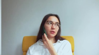 Genç ve çekici bir iş kadını telefonda konuşur ve belgelere bakar. Yüksek kaliteli FullHD görüntüler