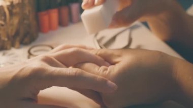 Profesyonel bir manikürcü, genç bir kızın tırnaklarını dosyayla temizler. Beyefendi müşterisine manikür yapıyor..
