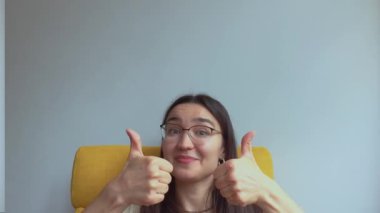 Genç ve çekici bir kız şaşırdı ve baş parmağını kaldırdı. Yüksek kalite 4K görüntü.