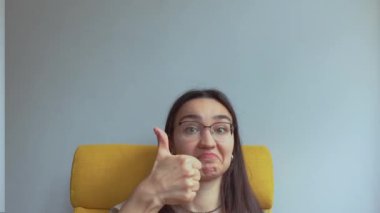 Genç ve çekici bir kız şaşırdı ve baş parmağını kaldırdı. Yüksek kalite 4K görüntü.