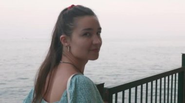 Genç ve çekici bir kadının portresi, deniz kıyısında yürüyor. Genç kız deniz manzarasının tadını çıkarıyor.