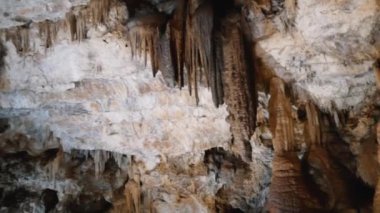 Tavandan sarkıtlar sarkan bir mağara. Mağara karanlık ve sarkıtlar aydınlık..
